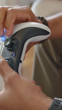 Vertical video: Entering frame hands pressing lit controller buttons, nudging stick at home playing