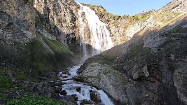 Low Drone Flight Through Lush Alpine Meadow Vegetation with Engstligen Waterfall Switzerland