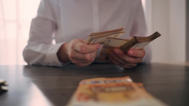 Woman organizing euro banknotes into stacks at desk, managing cash flow and personal business finances in professional office environment.Cash flow, money management, finance workflow concept