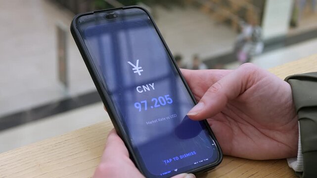 User checking the real-time CNY market rate against the USD on a mobile phone. Large blue digits display the exact value. Ideal for currency exchange, financial tracking, and global economic news