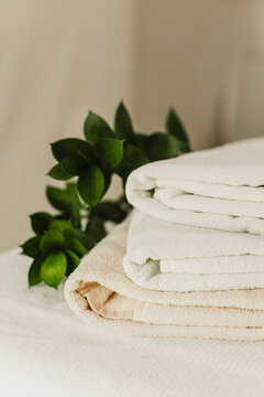 Minimalist still life of luxury spa essentials. White cotton towels with visible textured on a table.
