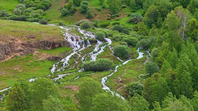 Aerial view of mountain streams from Konarli Waterfall flowing next to a lush green forest in Tercan, Erzincan Turkey