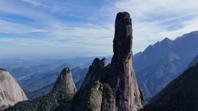 Drone footage descending toward the base of Dedo de Deus with the full granite formation visible.