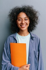 Obraz premium Female student portrait holding an orange folder for education profile and headshot use with friendly smile