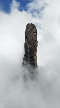 Rising drone shot from the rainforest canopy gradually revealing the full height of Dedo de Deus peak.