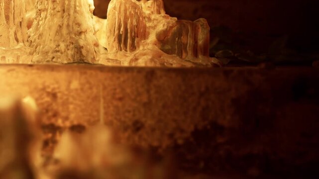 A candle burns softly beside a wax sculpture in a dark room. The light creates shadows and highlights the details on the sculpture. The atmosphere is warm and inviting as evening sets in.