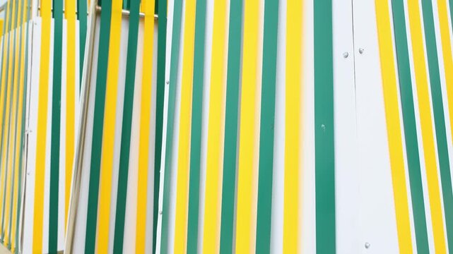Colorful plastic strips swaying on beach changing cabins in bright daylight