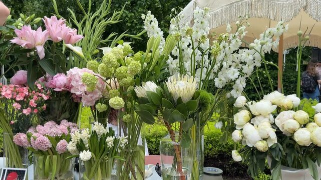 Floral arrangement with various flowers and greenery under parasol at outdoor event