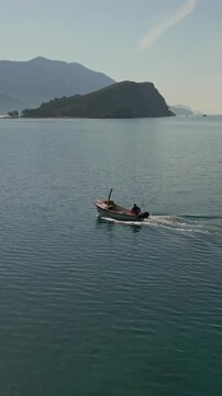 Fisherman on a boat sailing toward budva old town in montenegro