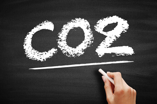 CO2 carbon dioxide chemical formula on a chalkboard. Hand underlining the gas symbol related to climate, emissions, and atmospheric science in an educational environment.