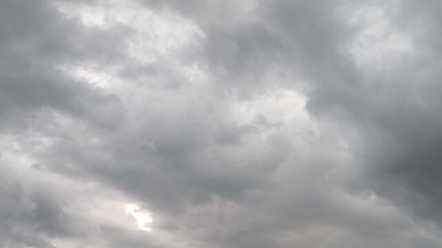 Heavy grey clouds cover the sky with a faint sun glowing at the bottom. This moody atmospheric footage provides a dramatic background for weather and emotional themes, weather forecast