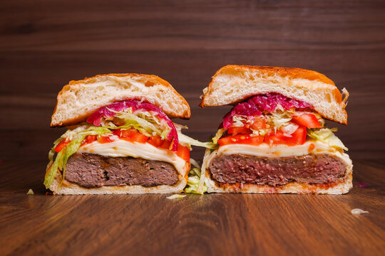 Panino tagliato a met&agrave; con hamburger di carne con due cotture diverse, provola, pomodori, insalata e cipolla caramellata servito in un pub