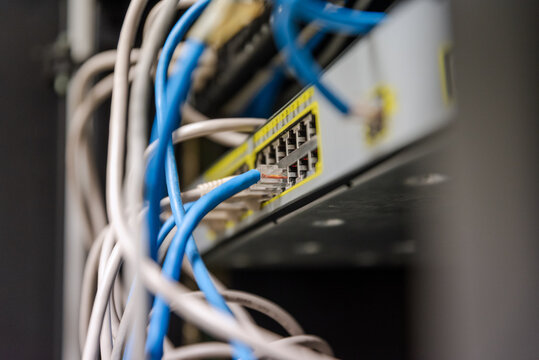 Close-up of a metallic junction box mounted on the back of a server rack with organized cables.