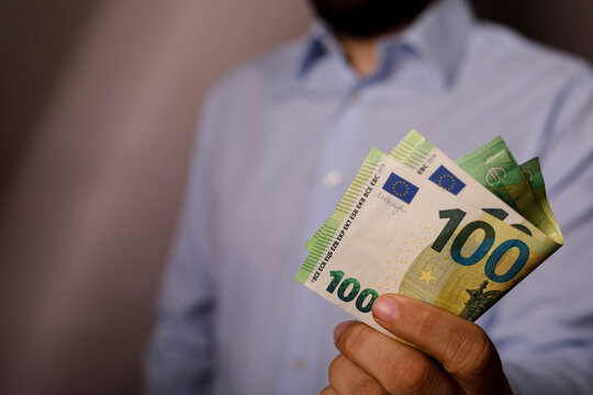 Man holding folded one hundred euro currency notes in his hand