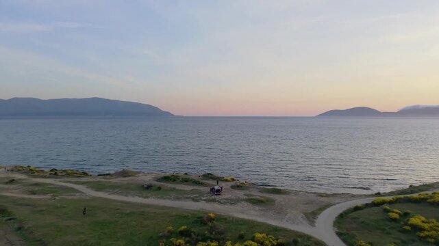 Aerial view of Vjose-Narte Delta Protected Area with yellow flowers on coastal hills and the sea at sunset Zvernec, Vlore County, Albania.