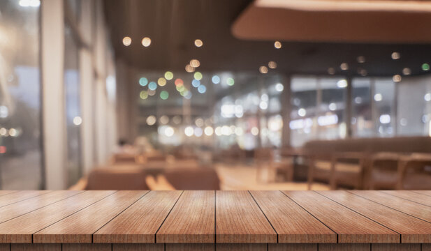 Empty wooden table top with lights bokeh on blur restaurant background.