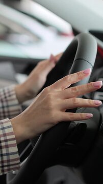 Vertical video Close up hands young woman auto driver car owner holding steering wheel buy new automobile dealership inside vehicle. Concept of car shopping, buying, and dealership.