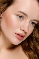 Fototapeta premium Young beautiful woman showcases natural beauty in vibrant studio light