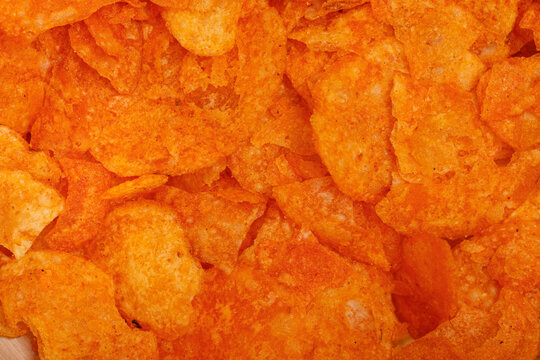 A vibrant close-up shot showcasing a pile of spicy orange flavored potato chips, perfect for food bl