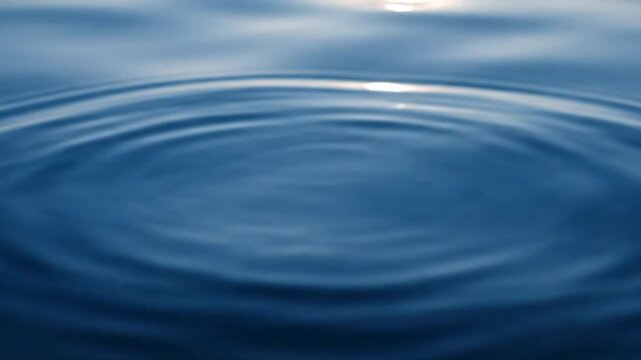 Concentric ripples on calm dark blue water surface.