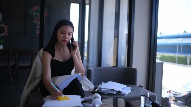 Businesswoman sitting indoor space wearing headphones while writing notes focused and productive work in a relaxed environment concepts of business education productivity and online learning.
