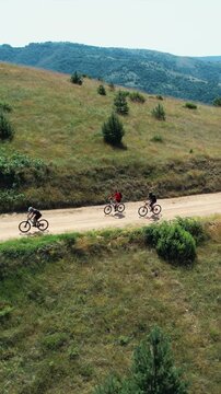 Cyclists biking along a dirt trail in a beautiful rural mountain setting with greenery