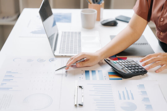 Analyzing Financial Data: A person's hands are visible as they point to charts and graphs on a desk, with a laptop, calculator, and smartphone nearby.