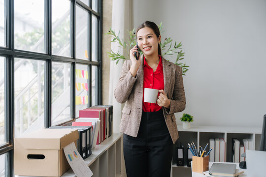 Businesswoman on the Phone: A confident businesswoman in professional attire takes a call while holding a coffee mug.