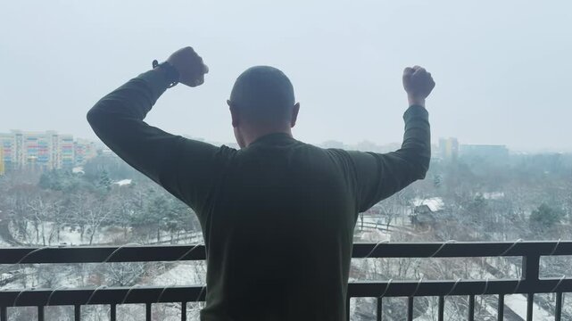 Joyful Man Dancing on Balcony with Winter City View in Bucharest