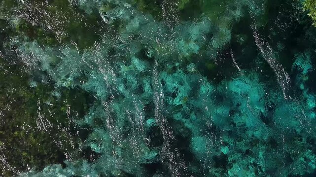 Aerial view of the crystal clear turquoise waters of the Blue Eye natural spring with underwater vegetation and rocks in Finiq, Vlore County, Albania.