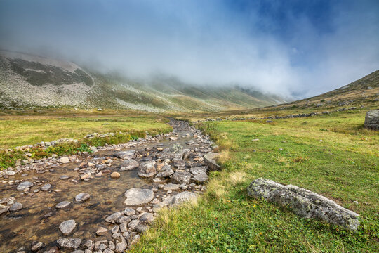 Clear mountain stream flowing through a lush alpine valley under a foggy sky in Kackar Mountains National Park, Rize, Turkey

