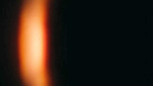 Warm orange light leak glow on dark black background