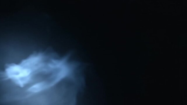 Blue smoke cloud rising from corner against black background