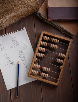 Vintage wooden abacus, paper sheet with financial calculations and old books