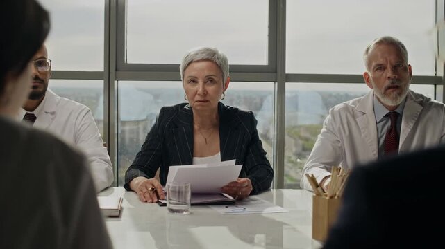 Pan shot of diverse group of middle aged specialists discussing reports during oil industry meeting. Ideal for corporate communication and energy sector marketing presentations