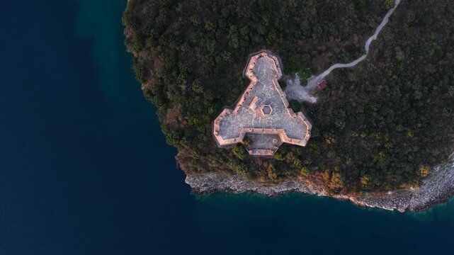 Aerial view of the triangular Porto Palermo Castle surrounded by deep blue sea and lush green vegetation in Porto Palermo, Qarku i Vlores, Albania.