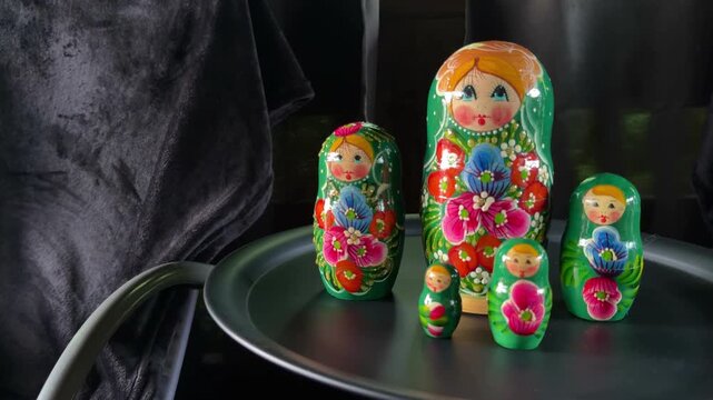 Nested Dolls Delight: A collection of beautifully painted Russian nesting dolls, with vibrant floral patterns and cheerful faces, displayed on a silver tray.