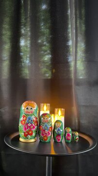 Russian Nesting Dolls and Candles: A set of traditional Russian nesting dolls, also known as Matryoshka dolls, are arranged on a silver tray with flickering candles, casting a warm and inviting glow.