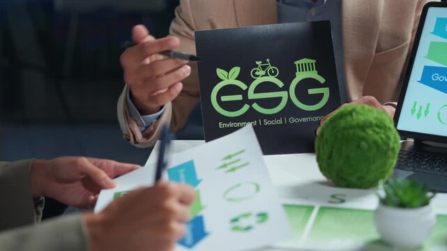 Professional team brainstorming for a corporate responsibility project, focusing on environmental, social, and governance principles shown on documents and a laptop during a meeting