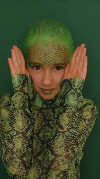 A girl in the guise of a snake with makeup on her face, imitating snake skin. Stylish Halloween Outfit