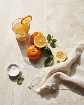 Refreshing citrus beverage with fresh oranges and lemons arranged on a textured surface