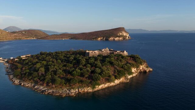 Aerial view of the historic Porto Palermo Castle surrounded by lush green trees and the blue waters of the Ionian Sea in Porto Palermo, Qarku i Vlores, Albania.