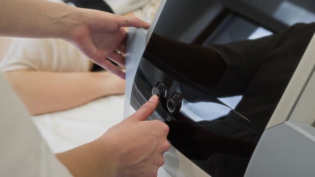 Caucasian female cosmetologist pressing button on modern aesthetic medical device during body treatment session. Footage perfect for beauty clinic promotions and wellness services marketing