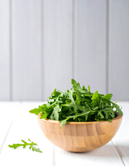 Fototapeta premium Green Arugula in Bamboo Bowl on White Wooden Background with Negative Space 