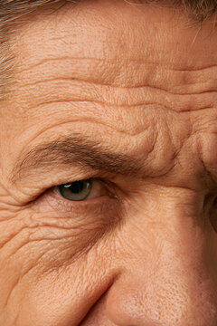 An intimate view of an aged face marked by deep wrinkles and frown lines, conveying doubt and concern