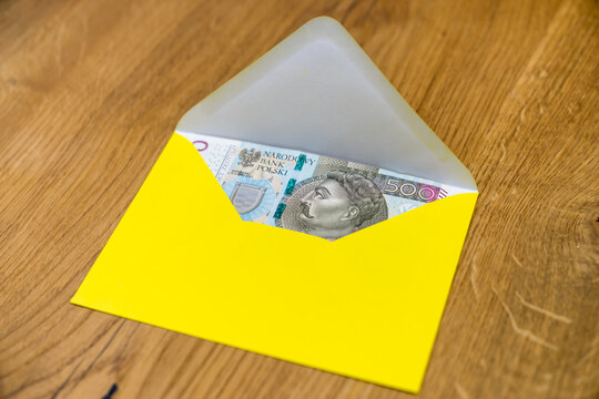 Polish banknotes in yellow envelope on wooden background