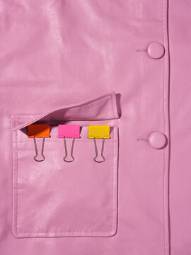 A pink leather jacket has 3 multicoloured foldback clips on the pocket