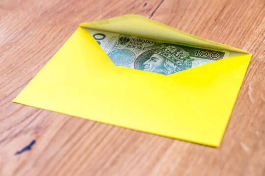 Polish banknotes in yellow envelope on wooden background