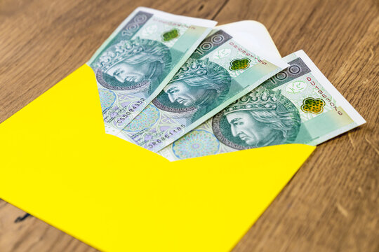 Polish banknotes in yellow envelope on wooden background