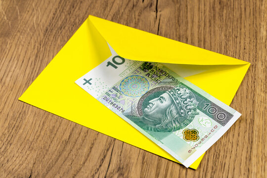 Polish banknotes in yellow envelope on wooden background
